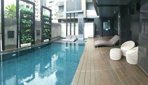 a swimming pool with two chairs and a building at Moda Condominium by Merryland in Chiang Mai