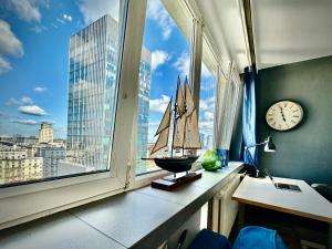 a window with a sailboat on a shelf with a clock at Super Apartament WHITE Warszawa 2x Metro Ścisłe Centrum WiFi 300 Mbs NEW in Warsaw