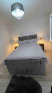 a bedroom with a large bed and a chandelier at Immaculate 1 bedroom apartment in Orpington in Orpington