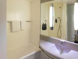 y baño blanco con lavabo y ducha. en ibis budget Tours Sud en Chambray-lès-Tours