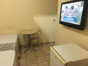 a room with a small table and a tv on the wall at HOTEL CENTER Ribeirão in Ribeirão Preto