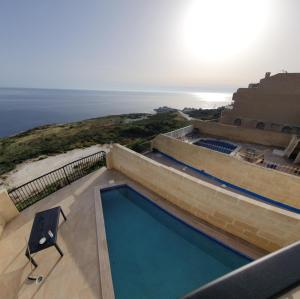 una piscina con una silla y el océano en Hili Complex, en Żebbuġ