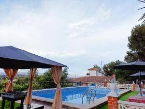 una piscina con sombrillas frente a una casa en Forest Villa,good view,biggest pool 78 m2,summer resort,Heights,cute squirrel,in City of misic, en Liria