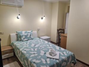 a bedroom with a bed with a blue comforter and two towels at SLATKI SNOVI II in Knin