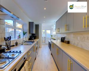 a large kitchen with white cabinets and wooden floors at Special Deal for 5-Bedroom House located near Coventry City Centre and with FREE Netflix Wi-fi and Parking -34HRC in Coventry