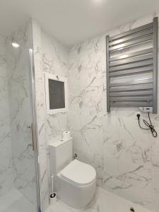 a white bathroom with a toilet and marble walls at Fantastic apartment Sant Adria Beach in Sant Adria de Besos