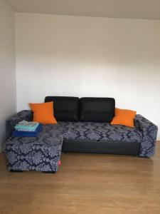 Sofá negro con almohadas naranjas en una habitación en Esthela home, en Funchal
