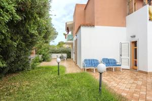 a patio with two blue chairs in the grass at Isola Blu, Jacuzzi & Pool by DomusAway in Porto San Paolo