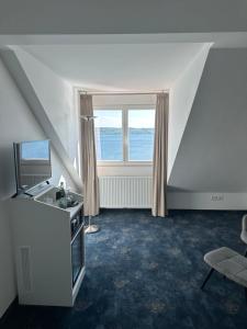 a living room with a large window and a television at Hotel Seegarten in Überlingen