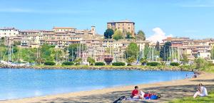 a group of people sitting on the beach near a body of water at Casa Clemy Lago di Bolsena in Capodimonte