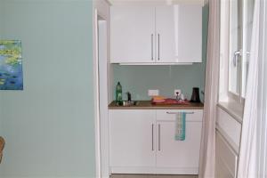 a kitchen with white cabinets and a counter at Studio beim Rhein in Flaach