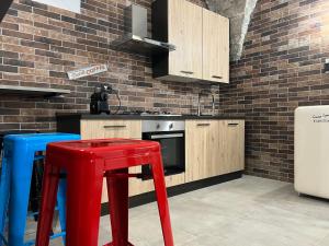 a kitchen with wooden cabinets and a red stool at Coccia resort / Norcia centro in Norcia