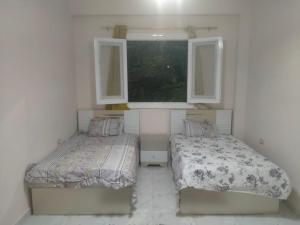 2 camas en una habitación con 2 ventanas en شقة فندقية فاخرة بمصرالجديدة روكسى, en El Cairo