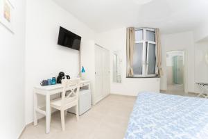 a white room with a bed and a desk and a computer at La casa di Bruna in Anacapri