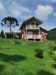 una casa roja en la parte superior de un campo verde en Cabanas Observatório, en Urubici