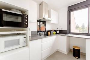 Biała kuchnia z kuchenką mikrofalową i oknem w obiekcie Joli appartement proche Paris Orly - Climatisé w mieście Morangis