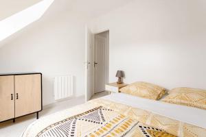 a white bedroom with a large bed and a dresser at Joli appartement proche Paris Orly in Morangis