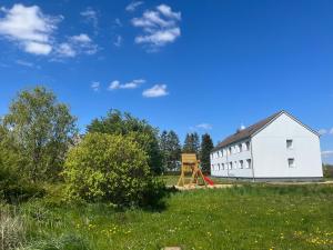 un granero blanco en un campo con parque infantil en Monteur-Pension N2 