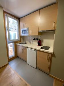 una pequeña cocina con armarios de madera y una ventana en Coqueto apartamento centro VIGO con WIFI en Vigo