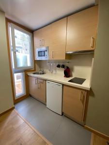 Elle comprend une petite cuisine avec des placards en bois et une fenêtre. dans l'établissement Coqueto apartamento centro VIGO con WIFI, à Vigo 5 autres photos