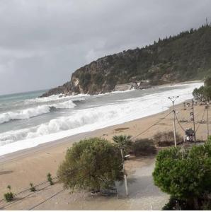 a sandy beach with waves in the ocean at Anxhelos Hotel in Himare