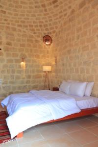 a bedroom with a white bed with a brick wall at Tache By The Lake in Fayoum Center
