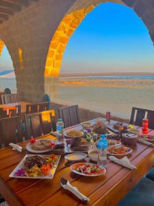 a table with plates of food on it with a view of the ocean at Tache By The Lake in Fayoum