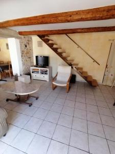 ein Wohnzimmer mit einer Treppe und einem Tisch in der Unterkunft Maison de village in La Tour-sur-Orb