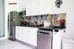 圣弗朗索瓦Oasis de détente - Appartement Le Colibri Blanc的配有白色橱柜和不锈钢冰箱的厨房