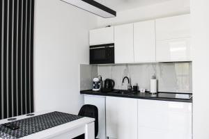 een witte keuken met witte kasten en een tafel bij Apartament Black-Niska z garażem podziemnym in Kielce
