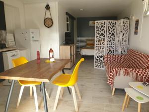 cocina y comedor con mesa y sillas amarillas en LE GÎTE DU CHEMIN ROUGE 