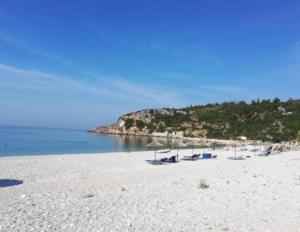 a beach with umbrellas and chairs and the ocean at Anxhelos Hotel in Himare