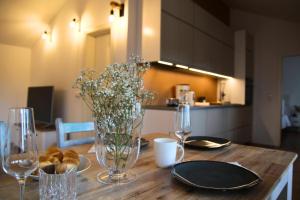 - une table en bois avec des assiettes, des verres et des fleurs dans l'établissement Chiemsee Apartments, à Altenmarkt an der Alz