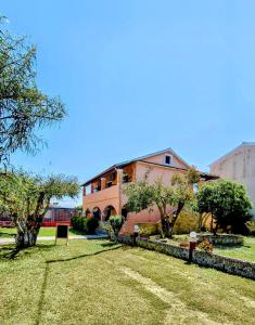 a pink building with trees in front of a yard at Anna Garden Sidari in Sidari