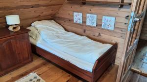 a small bed in a room with a wooden wall at Lawendowe Narie in Kretowiny