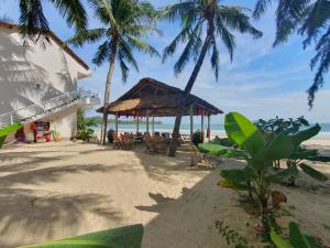 a beach with a restaurant and palm trees and the ocean at Lucky Spot Beach Bungalow in Song Cau