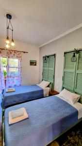 two beds in a room with green shuttered windows at Anna Garden Sidari in Sidari