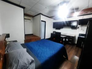 a bedroom with a blue bed and a desk at Hotel Garcias Suites, Linares in Linares