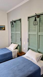 two beds in a room with green shuttered windows at Anna Garden Sidari in Sidari