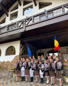 a group of people standing in front of a building with flags at Casa Baciu Colacu in Fundu Moldovei