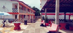 a patio with tables and chairs and a building at Flats quase beira mar ar piscinas até 8 pessoas caseiro in Itamaracá