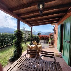 eine Terrasse mit einer Holzbank und Stühlen unter einer Pergola in der Unterkunft Agriturismo Tenuta La Fratta in Bagni di Lucca
