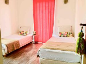 um quarto com duas camas e uma cortina vermelha em Casa Porti Vechju em Porto-Vecchio