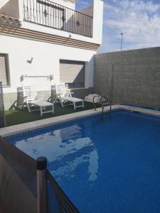- une piscine avec des chaises et une maison dans l'établissement LA MANCHEGUITA DE MADRIGUERAS 5 DORMITORIOS DOBLES CHALET CON PISCINA Y BARBACOA ideal familias 11 personas, 