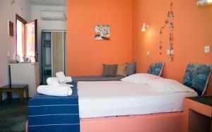 a bedroom with orange walls and a bed with towels at Helios Serifos in Livadi