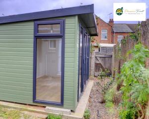 a green tiny house with a black roof at 5 Bedroom - 5 Bathroom house close to Coventry City Centre with spacious kitchen Free Wi-fi and garden - 56HRC in Coventry