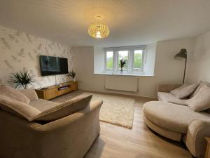 a living room with two couches and a flat screen tv at Wookey Hole Hideaway in Wookey Hole