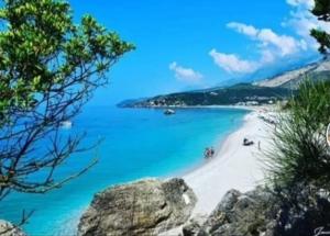 a beach with a white sand and blue water at Anxhelos Hotel in Himare