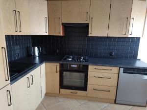 une cuisine avec des armoires en bois et un four à plaques de cuisson dans l'établissement Apartament Pod Bocianami, à Żelistrzewo