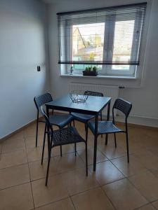 une table à manger avec quatre chaises et une fenêtre dans l'établissement Apartament Pod Bocianami, à Żelistrzewo 2 autres photos